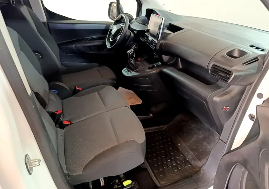 Vue intérieure côté conducteur du Peugeot Partner blanc 2021, montrant sièges noirs et tableau de bord avec écran tactile central.