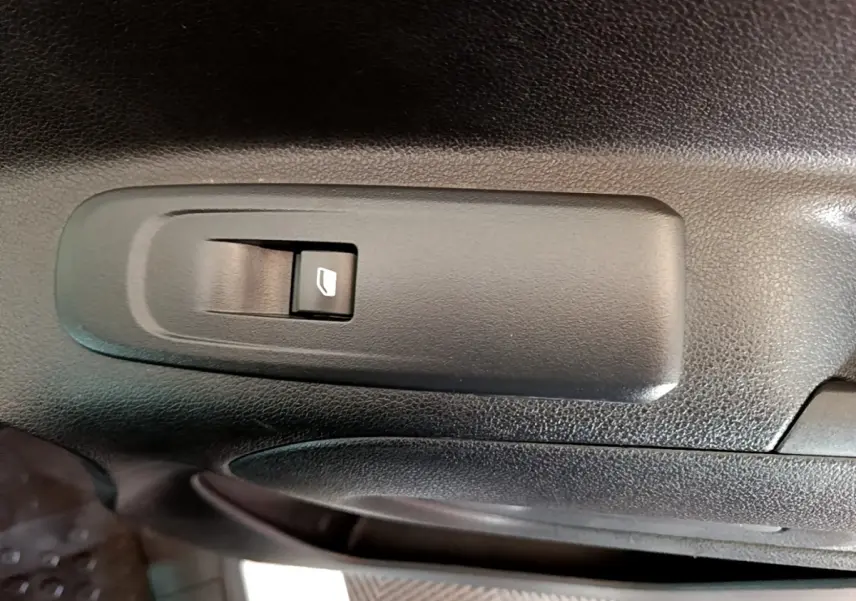 Gros plan sur le bouton de commande de la vitre électrique côté conducteur du Peugeot Partner blanc de 2021.