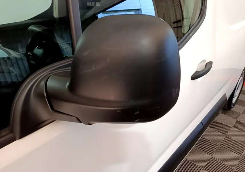 Vue rapprochée du rétroviseur noir côté conducteur sur la porte blanche d’un Peugeot Partner 2021.
