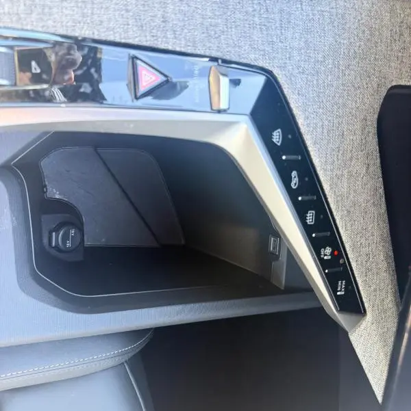 Gros plan sur la console centrale du Peugeot 3008 Hybrid gris, montrant les commandes de chauffage et prise 12V.