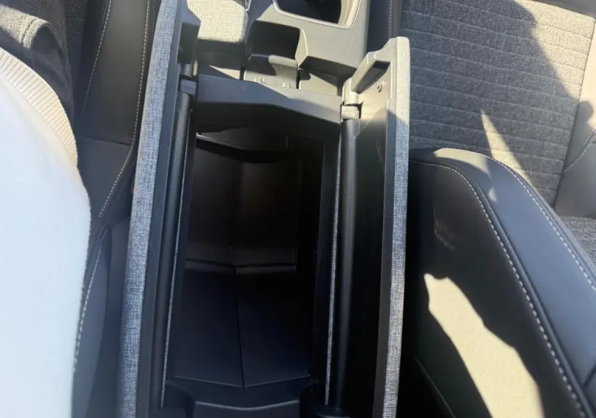 Vue plongeante sur l'accoudoir central ouvert et les sièges gris du Peugeot 3008 Hybrid 145 e-DCS6 Allure 2025.