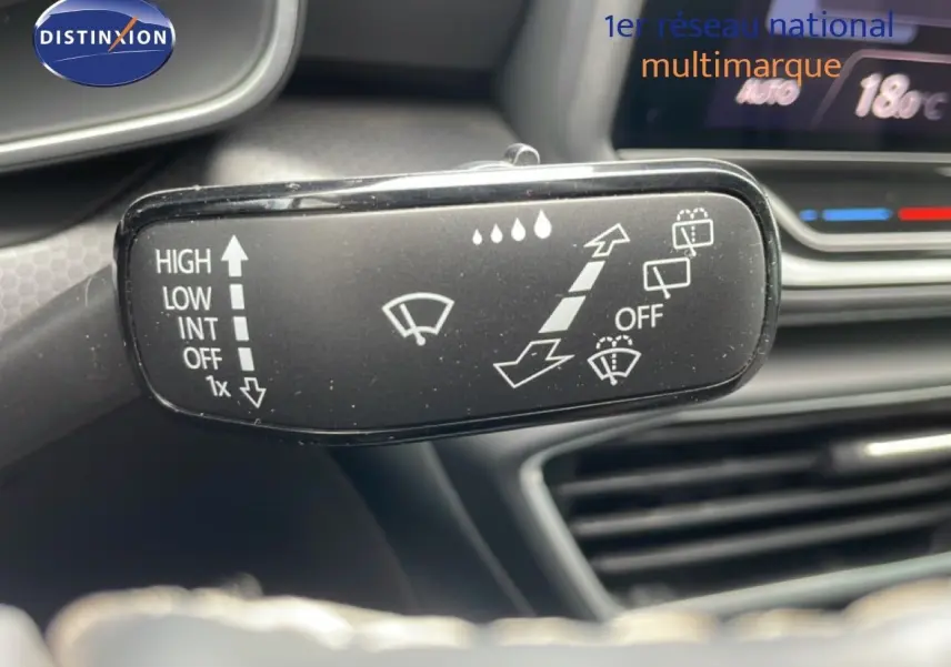Gros plan sur la commande d’essuie-glace du SEAT LEON 2025 blanc neige métal, avec tableau de bord en arrière-plan.