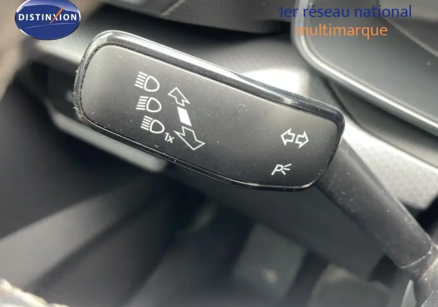 Gros plan sur la manette de clignotants noire à pictogrammes blancs dans l'habitacle d'une SEAT Leon blanc neige métal.