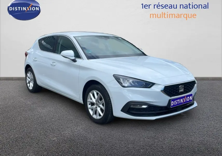 Vue 3/4 avant d'une SEAT Leon 2025 blanche neige métal avec jantes alliage et calandre noire distinctive.