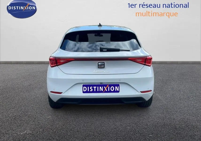 Vue arrière d'une SEAT Leon blanc neige métal 2025 avec feux LED reliés par une bande lumineuse rouge.
