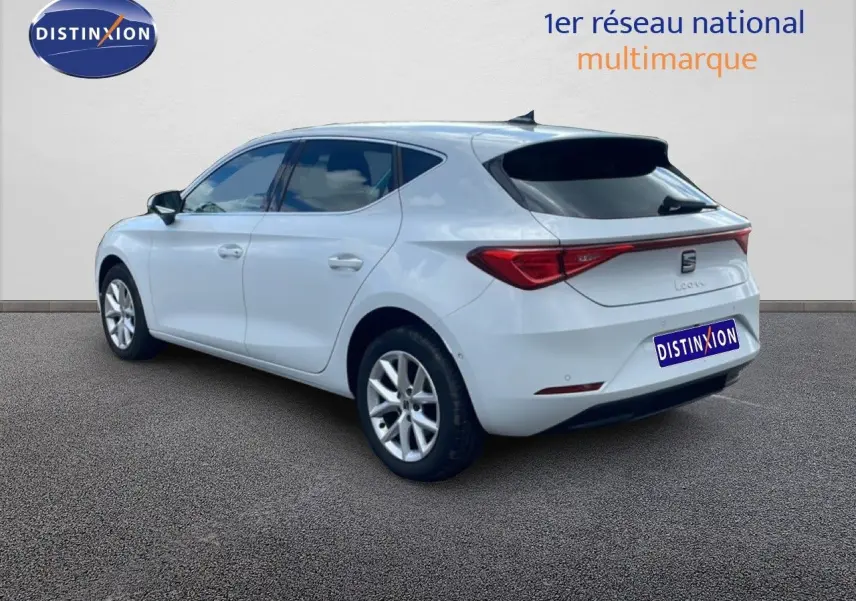 Vue 3/4 arrière droite d'une SEAT Leon blanc neige métal avec feux arrière LED et jantes alliage 16 pouces.