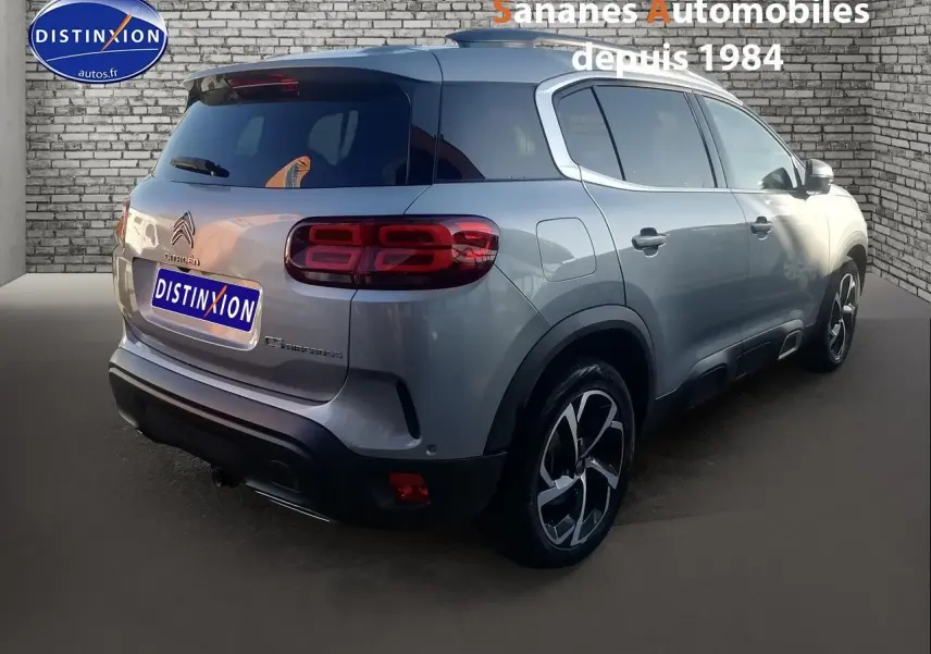 Vue 3/4 arrière droite d’un Citroën C5 Aircross gris métallisé avec jantes alliage 18 pouces et vitres teintées.