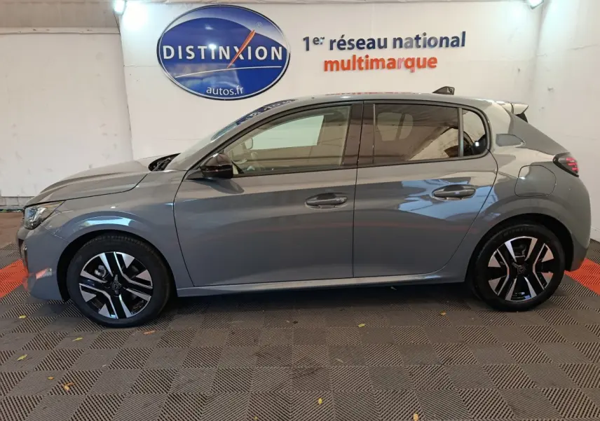 Profil droit d'une Peugeot 208 PureTech 100 S&S Allure gris foncé avec jantes noires et grises, en intérieur showroom.