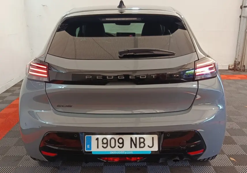 Vue arrière d'une Peugeot 208 gris foncé avec feux LED allumés dans un garage.
