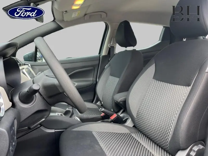 Vue intérieure côté conducteur de la Nissan Micra 2022 avec sièges bi-ton noir et gris et volant multifonction.