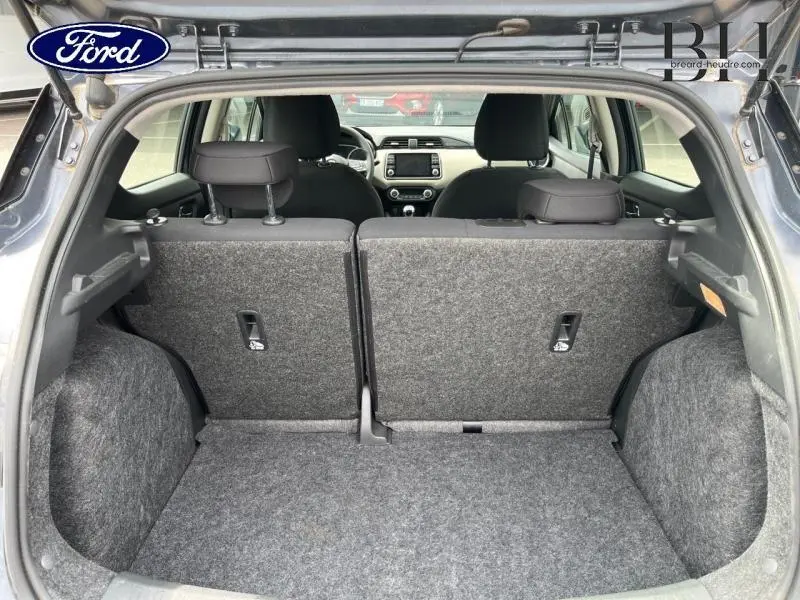 Coffre ouvert vu de l'arrière d'une Nissan Micra gris acier 2022 avec banquette arrière en tissu bi-ton noir et gris.