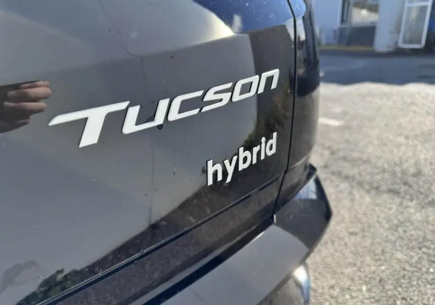Gros plan sur l'arrière noir abyss métallisé du Hyundai Tucson IV avec badges "Tucson" et "hybrid" visibles.