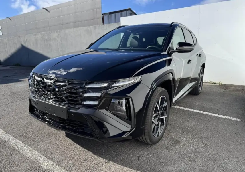 Hyundai Tucson IV noir abyss métal vu en 3/4 avant droit, avec calandre noire et jantes alliage distinctives.