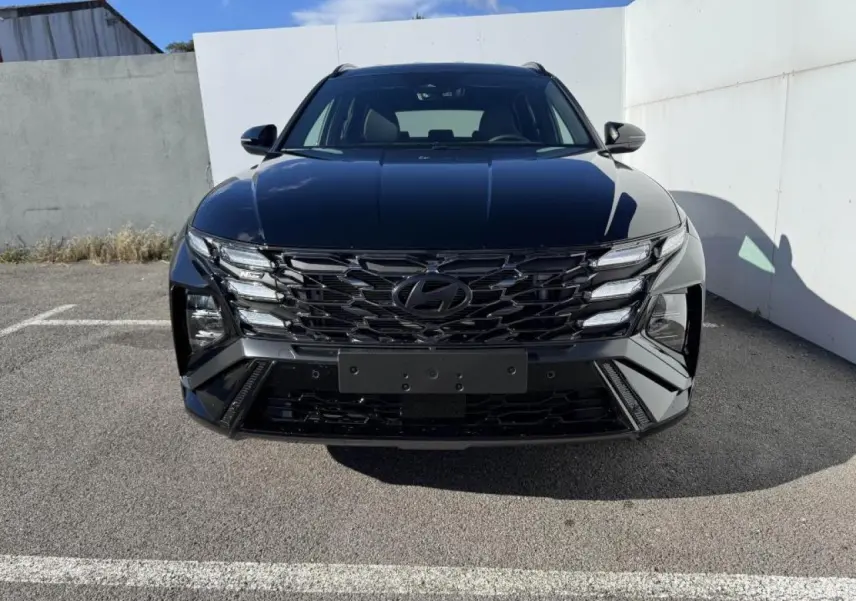 Vue frontale d'un Hyundai Tucson noir Abyss Metal avec calandre noire et phares LED distinctifs, stationné en extérieur.