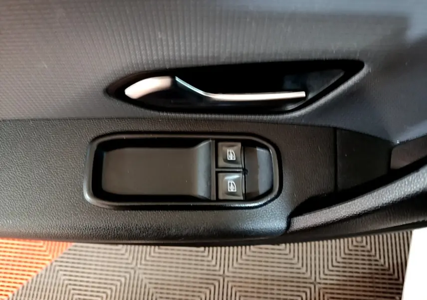 Poignée de porte intérieure noire avec commandes des vitres électriques sur Renault Express blanc, vue de profil côté conducteur.