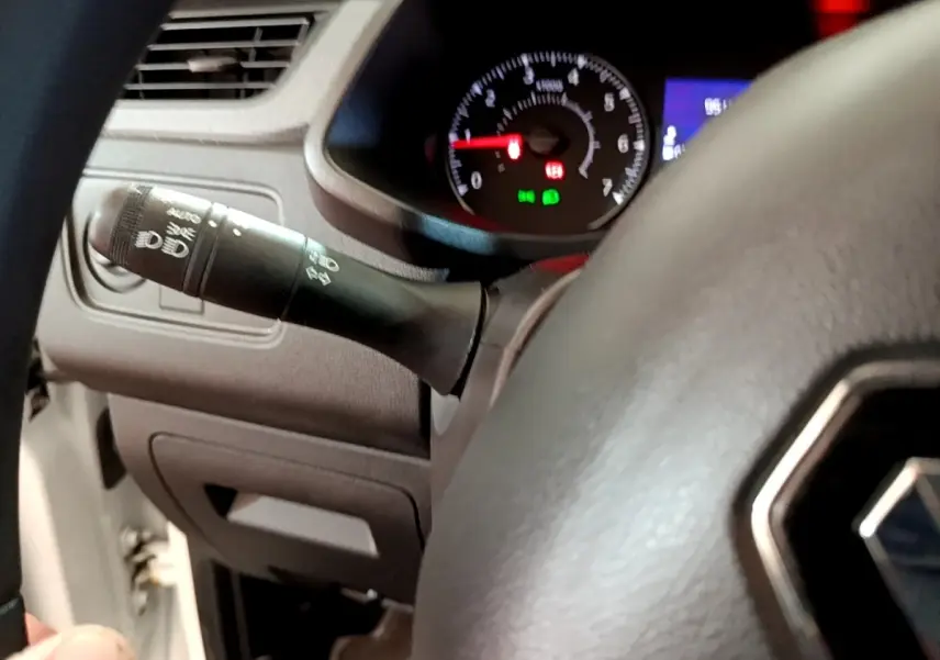 Gros plan sur le volant et la commande des phares du Renault Express blanc, tableau de bord avec compte-tours visible.