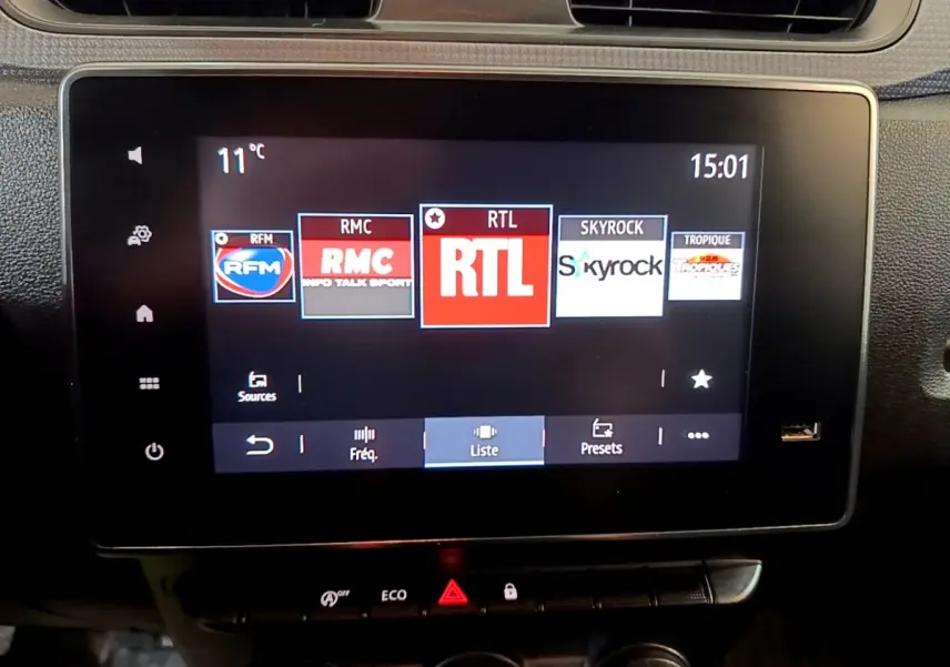 Écran tactile central du Renault Express blanc, affichant les stations radio, vue intérieure frontale.