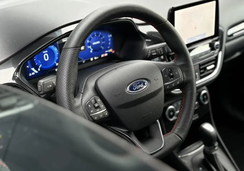 Vue rapprochée du volant ST-Line et du tableau de bord numérique bleu du Ford Puma gris Solar 2023.