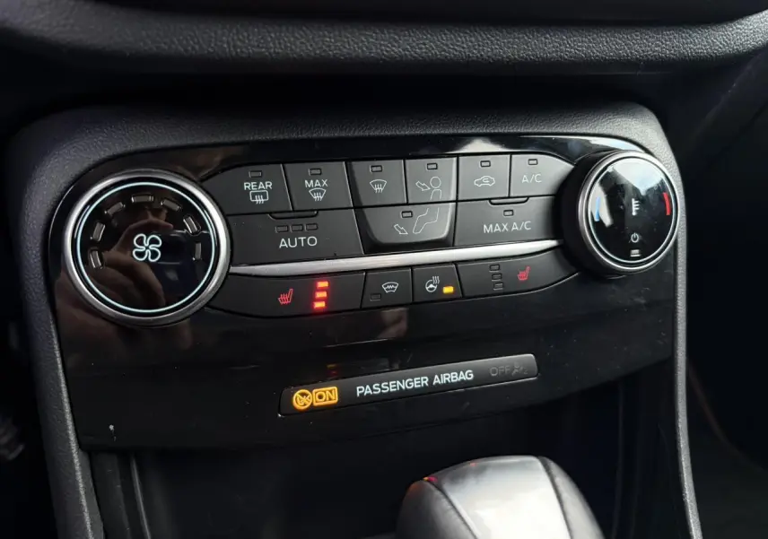 Gros plan sur la console centrale du Ford Puma 2023 gris Solar, montrant les commandes de climatisation et sièges chauffants.