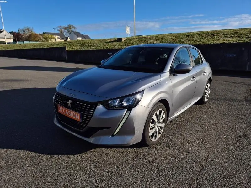 Peugeot 208 gris Artense vue 3/4 avant droit, avec calandre distinctive et feux LED en forme de griffes.
