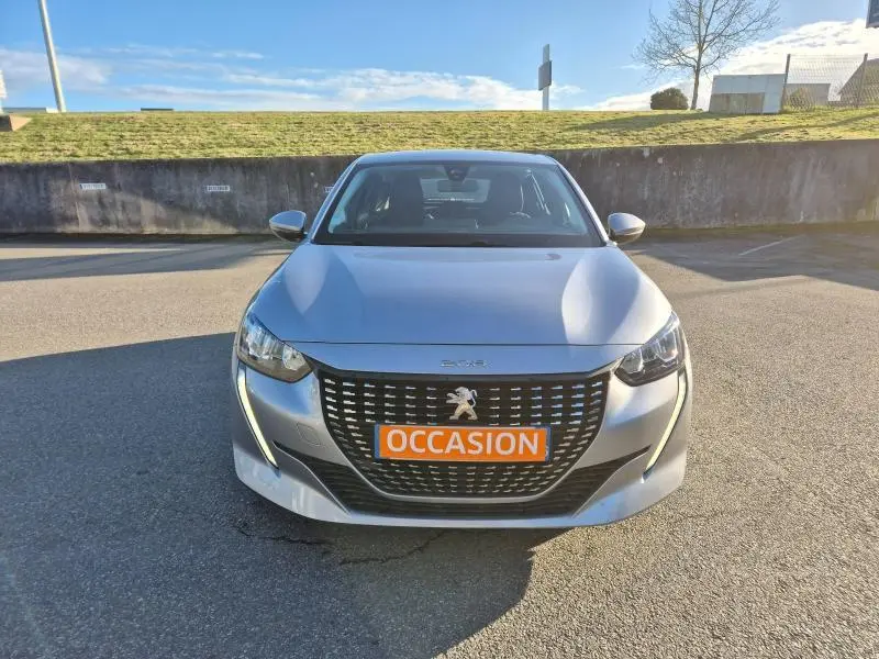 Vue avant d'une Peugeot 208 gris Artense avec calandre noire et plaque orange "OCCASION" en extérieur.