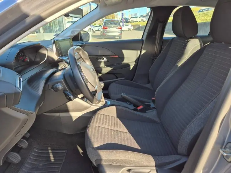 Intérieur avant droit de la Peugeot 208 1.5 BlueHDi 2020 avec sièges tissu gris et tableau de bord moderne.