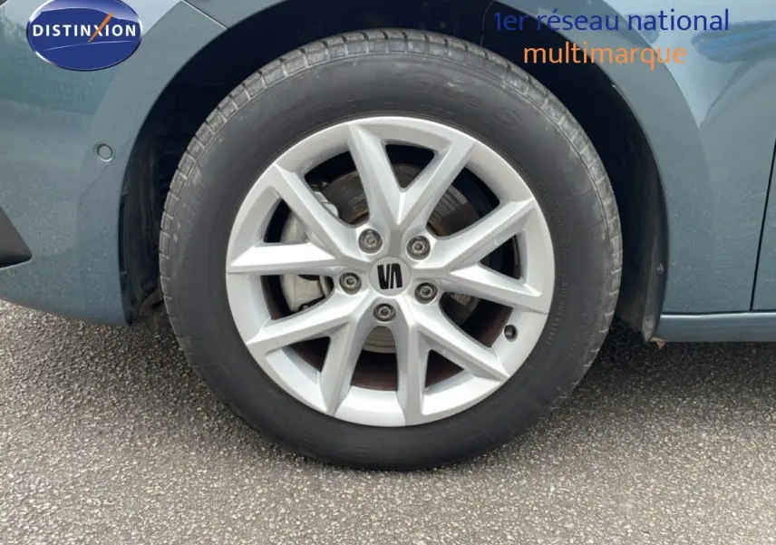Gros plan sur la roue avant droite d'une SEAT LEON bleu fjord, mettant en valeur la jante argentée à design moderne.