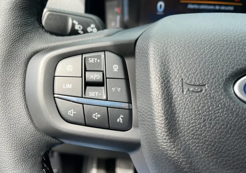 Gros plan sur les commandes du volant cuir multifonctions du Ford Ranger gris carbone 2025, côté gauche.