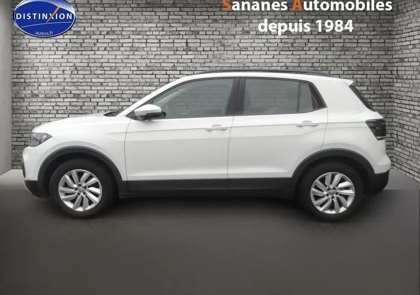 Profil côté gauche d'un Volkswagen T-Cross blanc 2020 avec jantes alliage et protections noires sur les passages de roues.