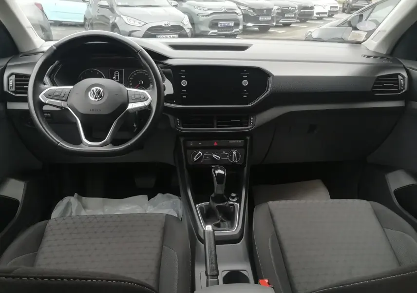 Vue intérieure avant du Volkswagen T-Cross 2020, tableau de bord noir avec écran tactile et volant multifonction.