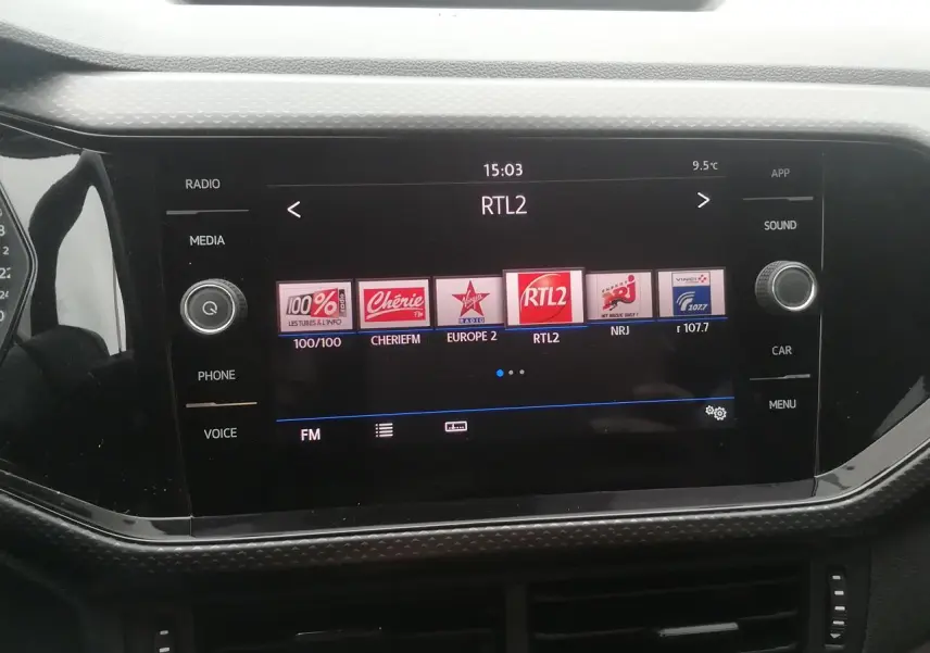 Vue rapprochée de l’écran tactile 8 pouces du Volkswagen T-Cross blanc affichant les stations radio FM.