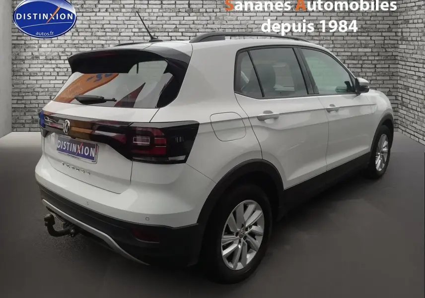 Vue 3/4 arrière droite d'un Volkswagen T-Cross blanc 2020 avec attelage et feux arrière foncés.