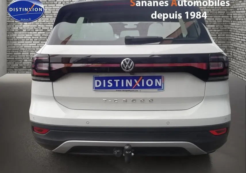 Vue arrière d'un Volkswagen T-Cross blanc avec feux arrière noirs et attelage de remorque visible.