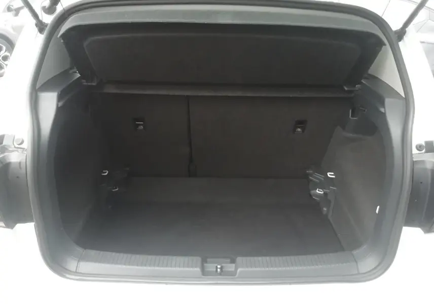 Coffre ouvert vu de l'arrière d'un Volkswagen T-Cross blanc, montrant l'espace de chargement vide et la garniture intérieure noire.