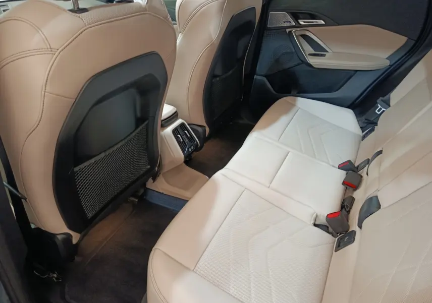 Vue intérieure arrière côté droit du BMW X1 xDrive25e M Sport 2024, sièges cuir beige et détails noirs.