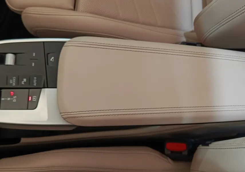 Gros plan sur l'accoudoir central beige et la console de commandes du BMW X1 xDrive25e M Sport 2024.