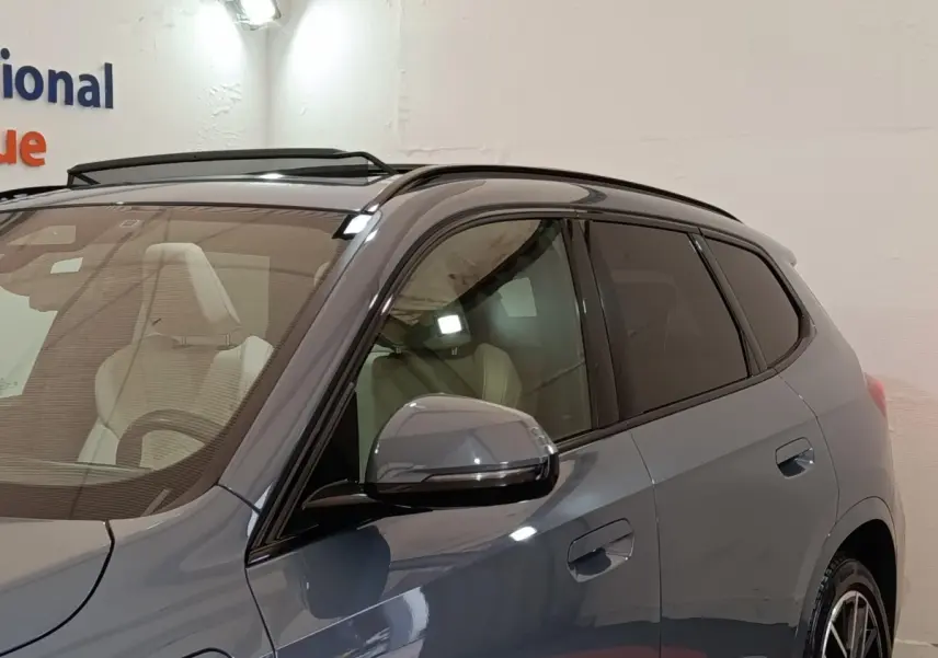 Vue de côté droit d'un BMW X1 xDrive25e M Sport gris foncé avec rétroviseur et vitres teintées visibles.