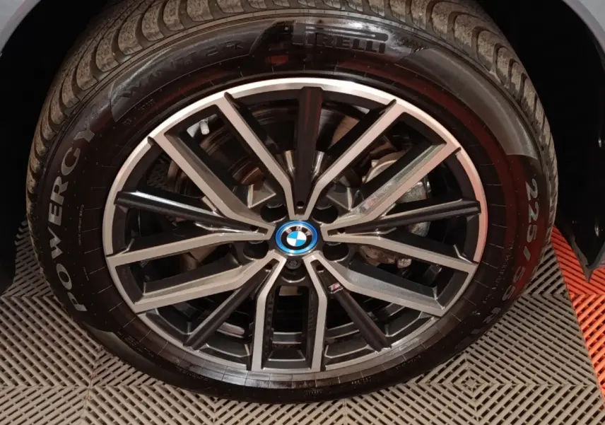 Gros plan sur la jante alliage noire et argentée d’un BMW X1 xDrive25e M Sport gris foncé, pneu Pirelli visible.