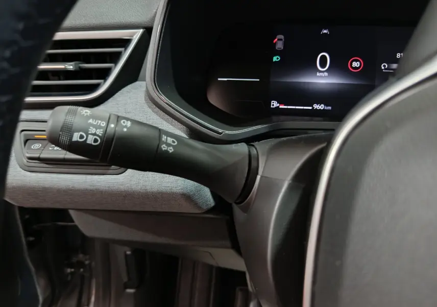 Gros plan sur la commande des phares et l'affichage numérique du combiné d'instruments dans une Renault Clio gris foncé 2025.