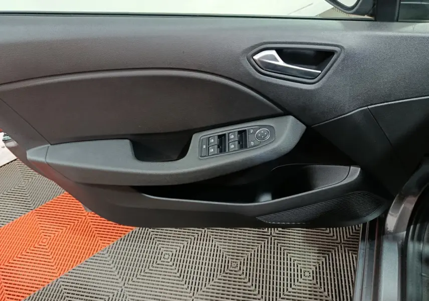 Vue intérieure côté gauche de la porte d'une Renault Clio gris foncé avec commandes de vitres et poignée argentée.