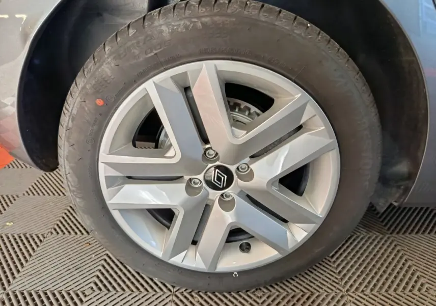 Gros plan sur la jante alliage argentée avec logo Renault d'une Renault Clio gris foncé, roue avant droite visible.