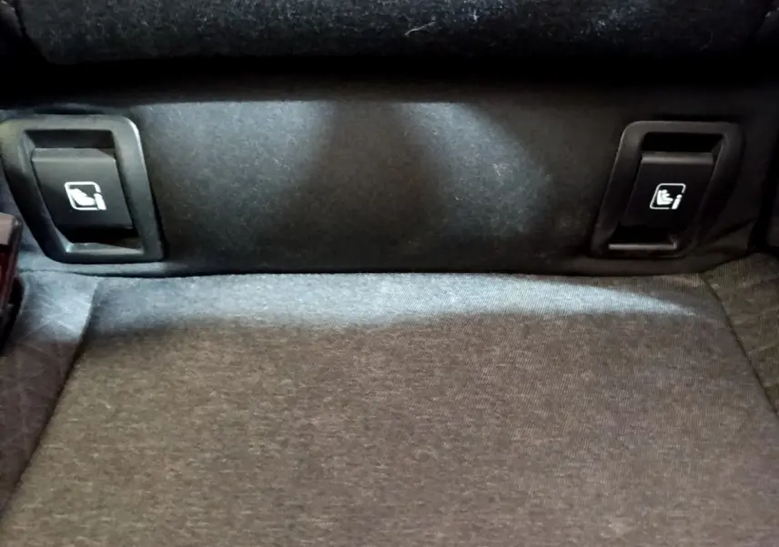 Gros plan sur les commandes de rabattement des sièges arrière dans le coffre d'une Renault Clio blanche Business Blue dCi 115.