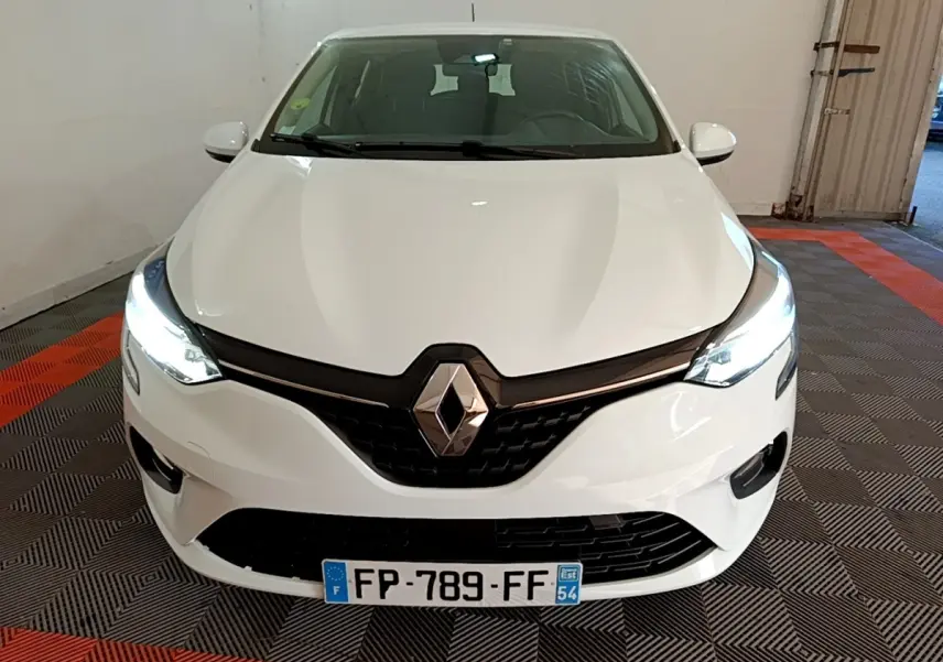 Vue avant d'une Renault Clio Business Blue dCi 115 blanche avec phares LED allumés dans un garage.