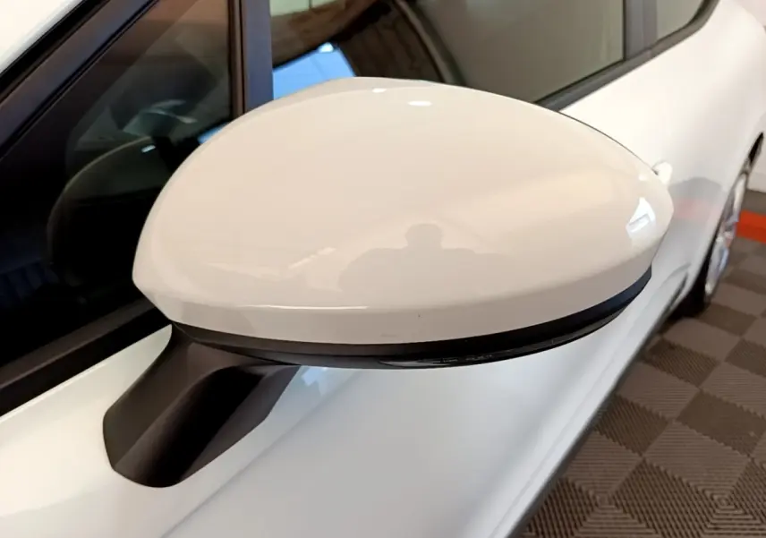 Rétroviseur blanc côté conducteur d'une Renault Clio Business Blue dCi 115 vue en gros plan sur fond intérieur.