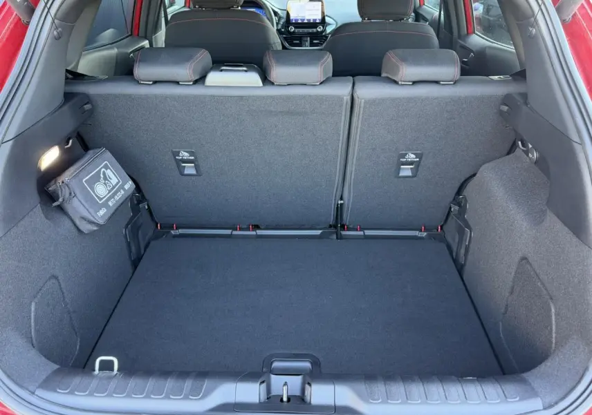 Vue intérieure du coffre ouvert d’un Ford Puma rouge Fantastic 2023, montrant les sièges arrière et la console centrale.