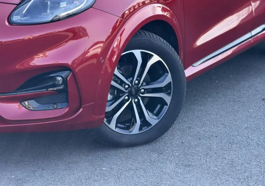 Gros plan sur la roue avant droite et le pare-chocs d’un Ford Puma rouge Fantastic avec jante alliage diamantée.