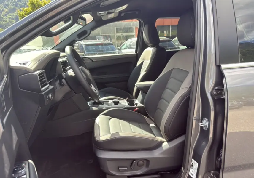 Vue intérieure côté conducteur du Volkswagen Amarok Simple Cabine V6 240 BVA10 Aventura 2026 en gris foncé avec sièges cuir noirs.