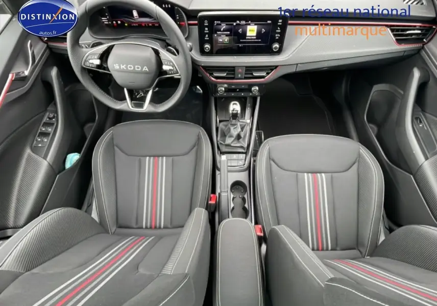 Vue intérieure frontale du Skoda Kamiq noir 2026, mettant en valeur le volant cuir, les sièges sport à bandes rouges et la console centrale.