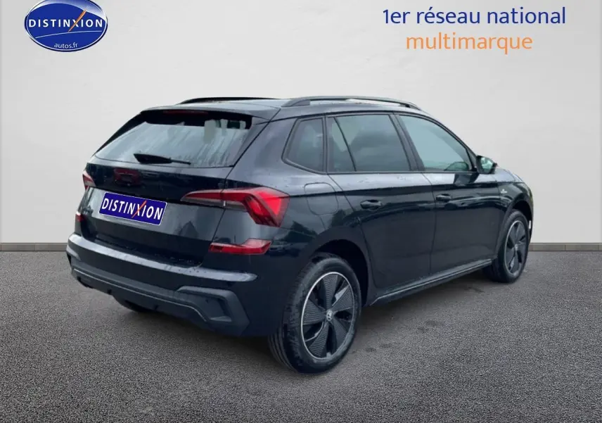 Vue 3/4 arrière droite d'un Skoda Kamiq noir avec jantes alu et barres de toit visibles sur fond neutre.