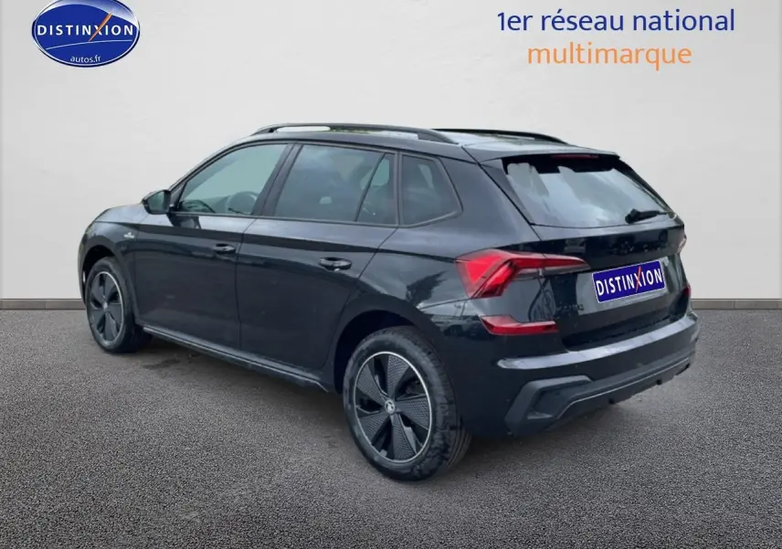 SKODA KAMIQ noir vue 3/4 arrière droit, jantes alu noires et barres de toit visibles sur fond clair.